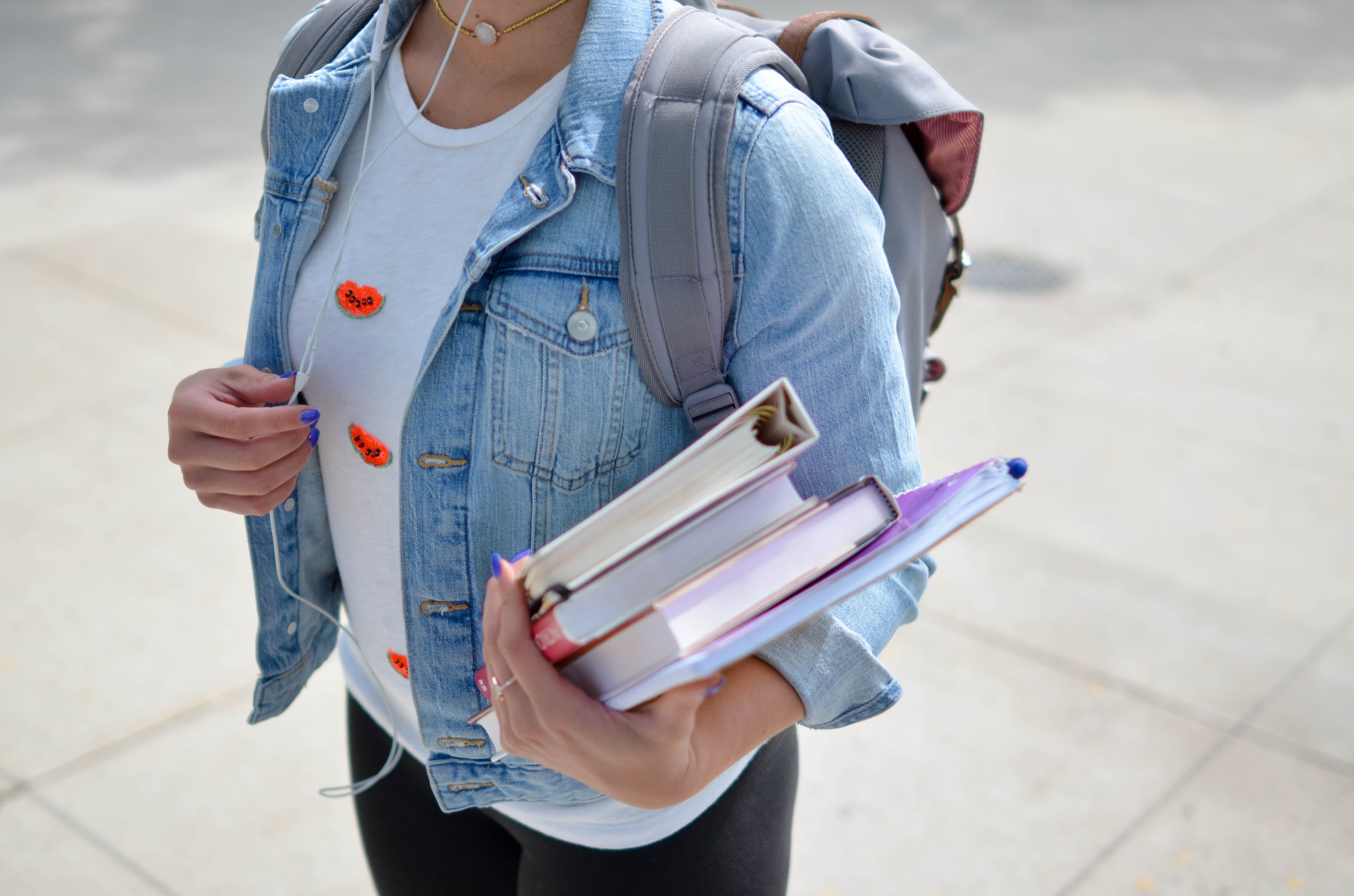 Student wearing backpack holding books